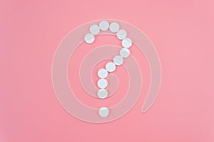 Question mark made from medical pills on a pink background. Treatment theme concept