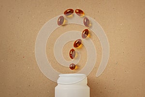 Question mark made of omega 3 Fish Oil capsules on recycled paper background - Concept of supplement, vitamins and healthy eating