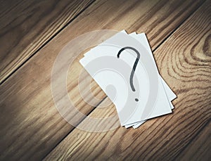 Question mark in paper on a wood background.