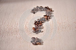 Question-mark symbol made from coffee crops on beige background.