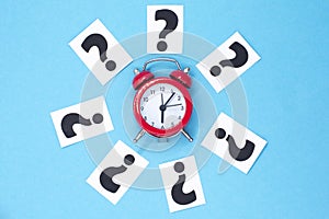 A question mark on a white sheet and a red alarm clock . FAQ frequency asked questions, Answer, Information and Brainstorming