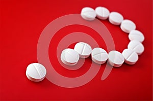 Question mark of white tablets on red