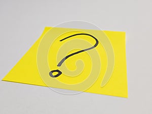 Question mark on yellow sticky note on white surface concept