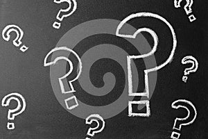 Question marks drawn with chalk on blackboard, top view