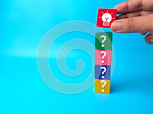 Question marks and light bulb icon on wooden blocks