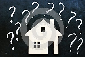 Question marks and model of home. Mortgage or buy and rent property