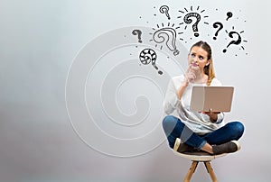 Question marks with young woman using her laptop