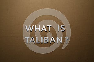 the question what is taliban laid with silver metal letters on rough tan khaki canvas fabric photo