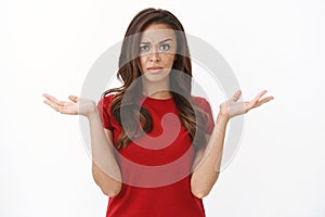 Questioned and frustrated disappointed brunette female in red t-shirt raise eyebrow skeptical and suspicious, shrugging