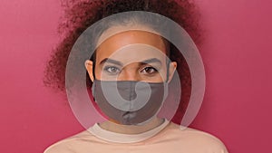 Questioning or studying look wearing reusable face mask African American charming girl in peachy t-shirt, to prevent