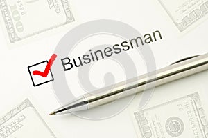 Questionnaire: businessman choice, marked checkbox with a silver pen on paper and dollars background. Careers survey