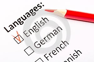 Questionnaire concept. Languages with English, German, French, Spanish checkboxes with red pencil. Close up image with focus on th