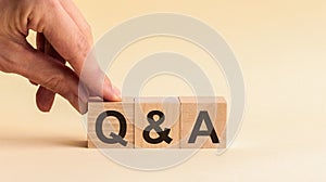 Questions and answers concept. Hand putting wood block cube with alphabet Q A on table. Yellow background