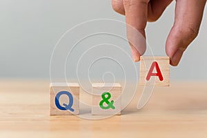 Questions and answers concept. Hand putting wood block cube with alphabet Q&A on wooden table