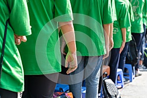 Queue of Asian teenagers in green t-shirt uniform standing in line