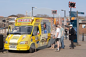 Queue at a van for ice cream on a sunny day at the harbor in Bristol, UK