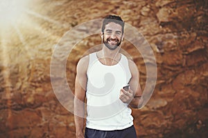 Queueing up my speed playlist. Portrait of a young man listening to music on earphones while out for a run.