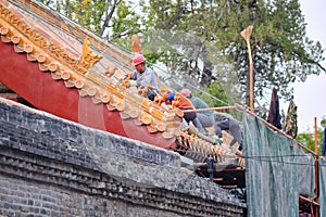 Workers repairing roof figure decorations and architectural details at the Temple of Confucius in Qufu, China