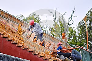 Workers repairing roof figure decorations and architectural details at the Temple of Confucius in Qufu, China