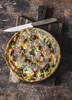 Quiche with kale, chicken, zucchini, sweet pepper, ham, mozzarella cheese on a wooden cutting board, top view. Delicious snack,