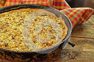 Quiche pie with chicken, green pepper, ham and mushroom in blac