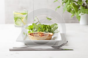 A quiche on a white plate with garnish