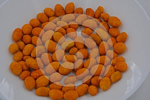 Quick food, snacks, salted battered peanuts and salted casings are arranged on a white glass plate.