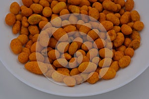Quick food, snacks, salted battered peanuts and salted casings are arranged on a white glass plate.