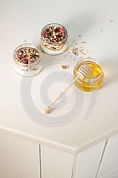 Quick healthy breakfast greek yogurt, honey, granola with dried berries and nuts in glass jar on stone table. Homemade granola par