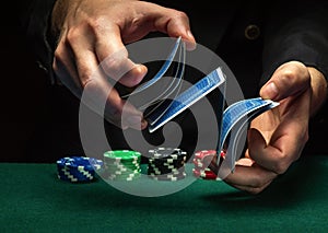 Quick shuffling of playing cards by the hands of an experienced dealer or croupier in a poker club on a green table with playing