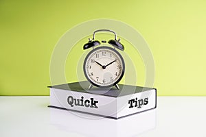 QUICK TIPS text, Alarm Clock and book on green background.