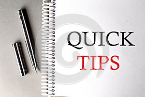 QUICK TIPS text on a notebook with pen on grey background
