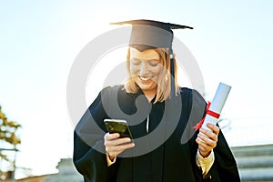 The quickest way to tell everyone about her big day. student using her cellphone on graduation day.