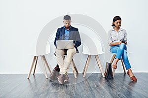 Quickly doing final preparations before the big presentation. Full length shot of two young businesspeople sitting down