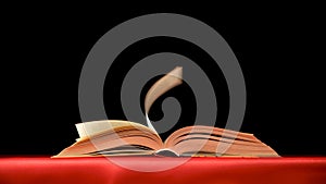 Quickly flipping pages of a thick book on a red black background