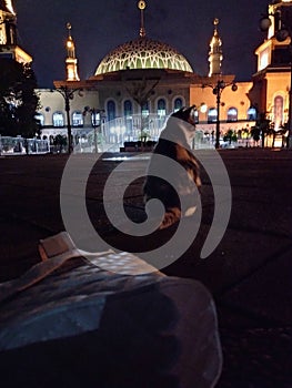 quiet atmosphere at night in an islamic mosque with a cat facing the mosque