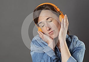 Quiet beautiful middle aged woman listening to relaxing music