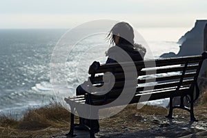 Quiet contemplation black jacketed girl on a cliff bench by sea