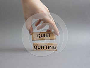 Quiet quitting symbol. Concept word Quiet quitting on wooden blocks. Beautiful grey background. Businessman hand. Business and