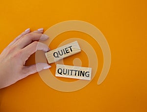 Quiet quitting symbol. Concept word Quiet quitting on wooden blocks. Beautiful orange background. Businessman hand. Business and