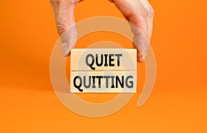 Quiet quitting symbol. Concept words Quiet quitting on wooden blocks. Beautiful orange table orange background. Businessman hand.