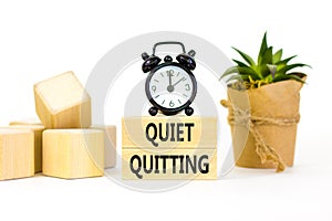 Quiet quitting symbol. Concept words Quiet quitting on wooden blocks. Beautiful white table white background. Black alarm clock.