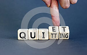 Quiet quitting symbol. Concept words Quiet quitting on wooden cubes. Businessman hand. Beautiful grey table grey background.