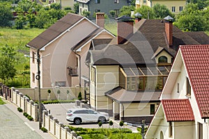 Quiet residential area with new expensive two- story cottages with brick fence and tile roofs and white sport car parked in front