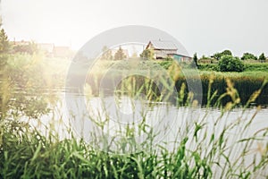 Quiet river, green grassy shore and russian village countryside background