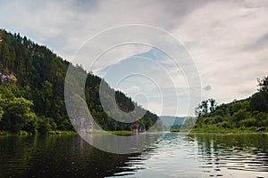 Quiet river between mountains and hills overgrown with coniferous forest