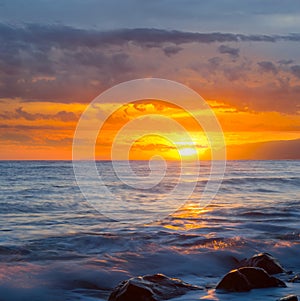 Quiet stony sea coast at the dramatic sunset