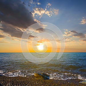 Quiet stony sea coast at the dramatic sunset