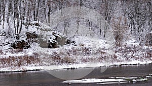 Quiet transparent river with spots of white snow on the shore