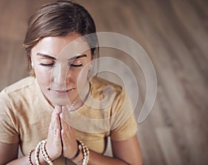 The quieter you become, the more you hear. an attractive young woman sitting indoors and using mala beads during her